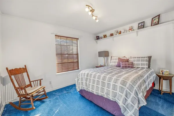 a bedroom with a bed chair and wooden floor