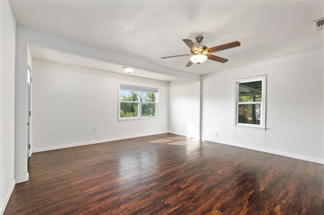 a view of an empty room with window and wooden floor