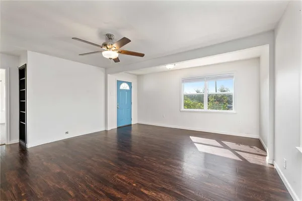 an empty room with wooden floor chandelier fan and windows