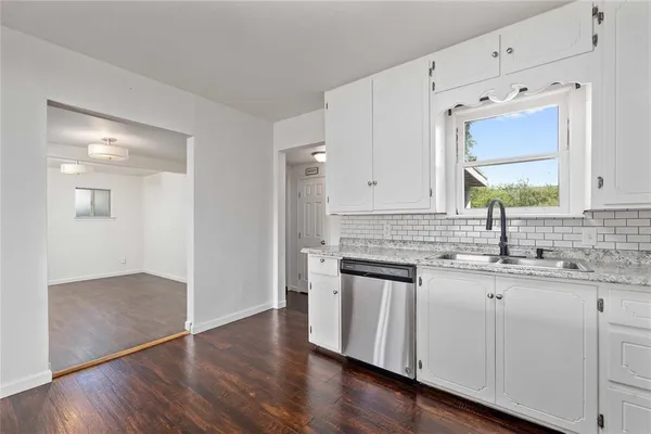 a kitchen with stainless steel appliances granite countertop a sink and cabinets with wooden floor