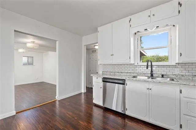 a kitchen with stainless steel appliances granite countertop a sink and cabinets with wooden floor