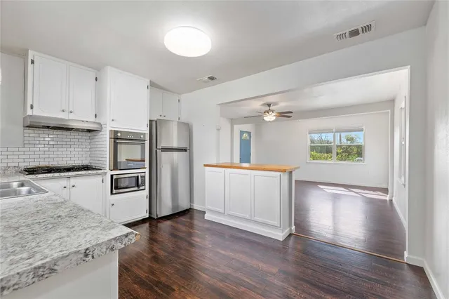 a kitchen with granite countertop a refrigerator and a stove top oven