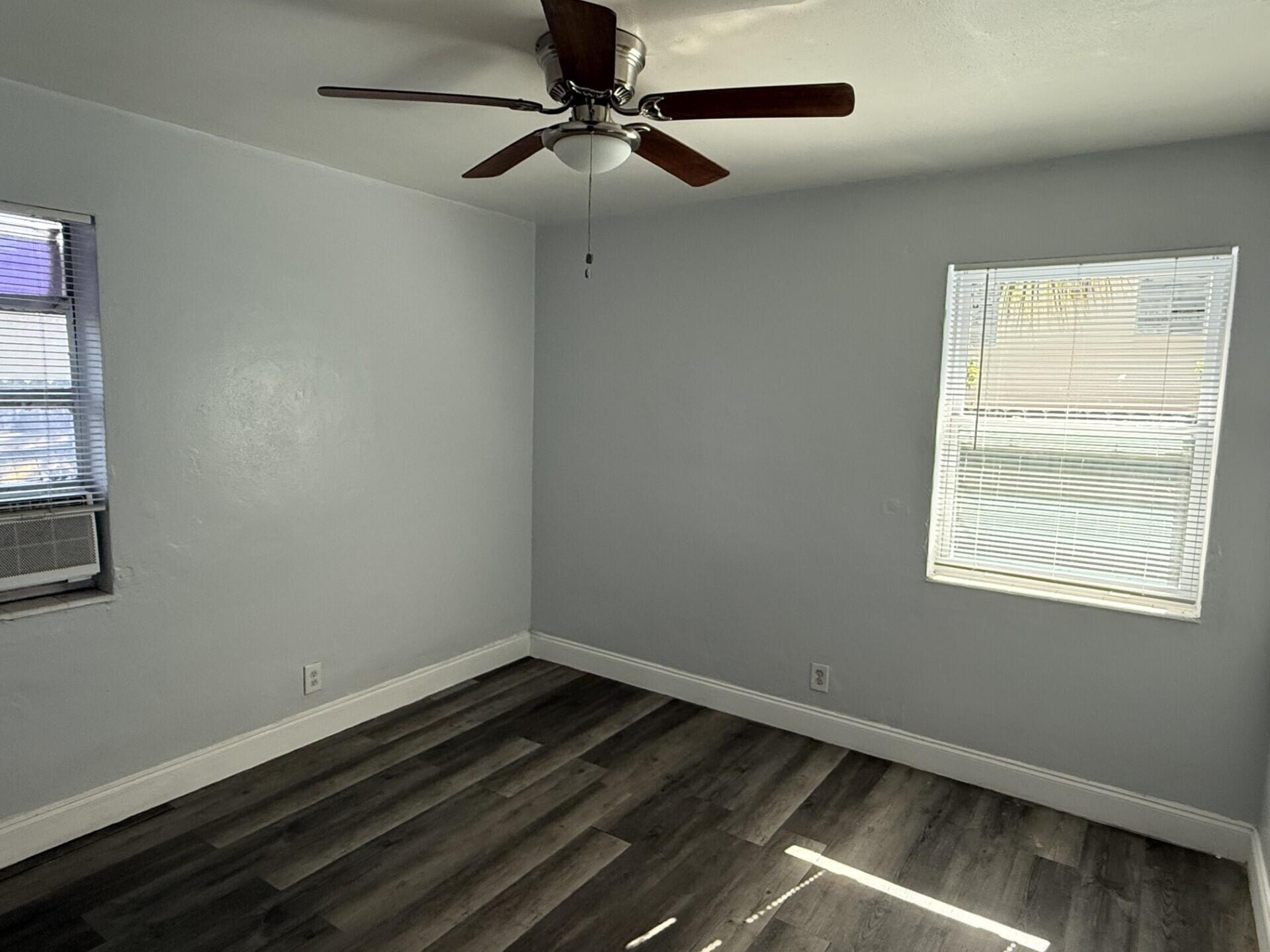 131 East 27th Street, Unit 4 Riviera Beach, FL 33404 - Photo 5 of 10 a room with wooden floor a ceiling fan and windows
