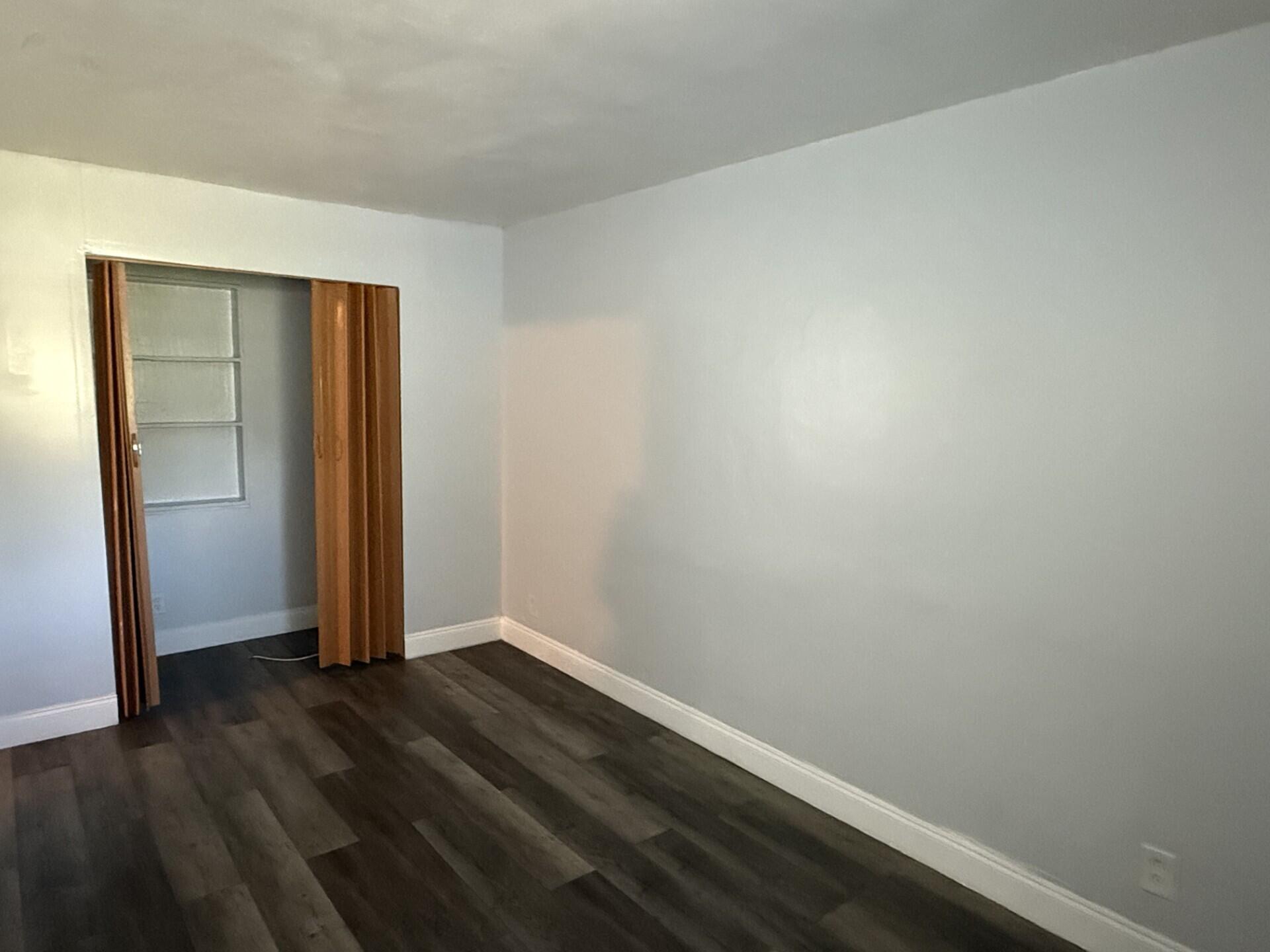 131 East 27th Street, Unit 4 Riviera Beach, FL 33404 - Photo 7 of 10 an empty room with wooden floor and closet