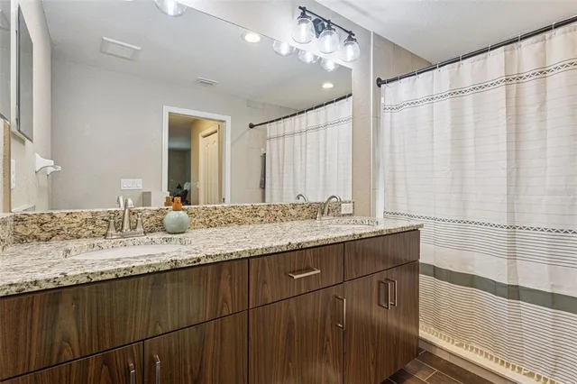 a bathroom with a granite countertop sink a mirror and a shower