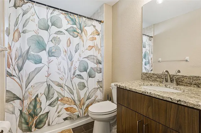 a bathroom with a granite countertop toilet sink and mirror