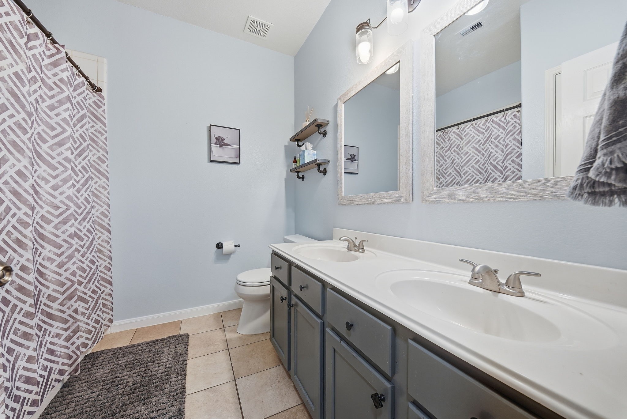 2223 Lazy Trail Path Court Spring, TX 77373 - Photo 11 of 23 Bright and airy bathroom featuring dual sinks, elegant fixtures, and a modern shower curtain for a stylish touch.