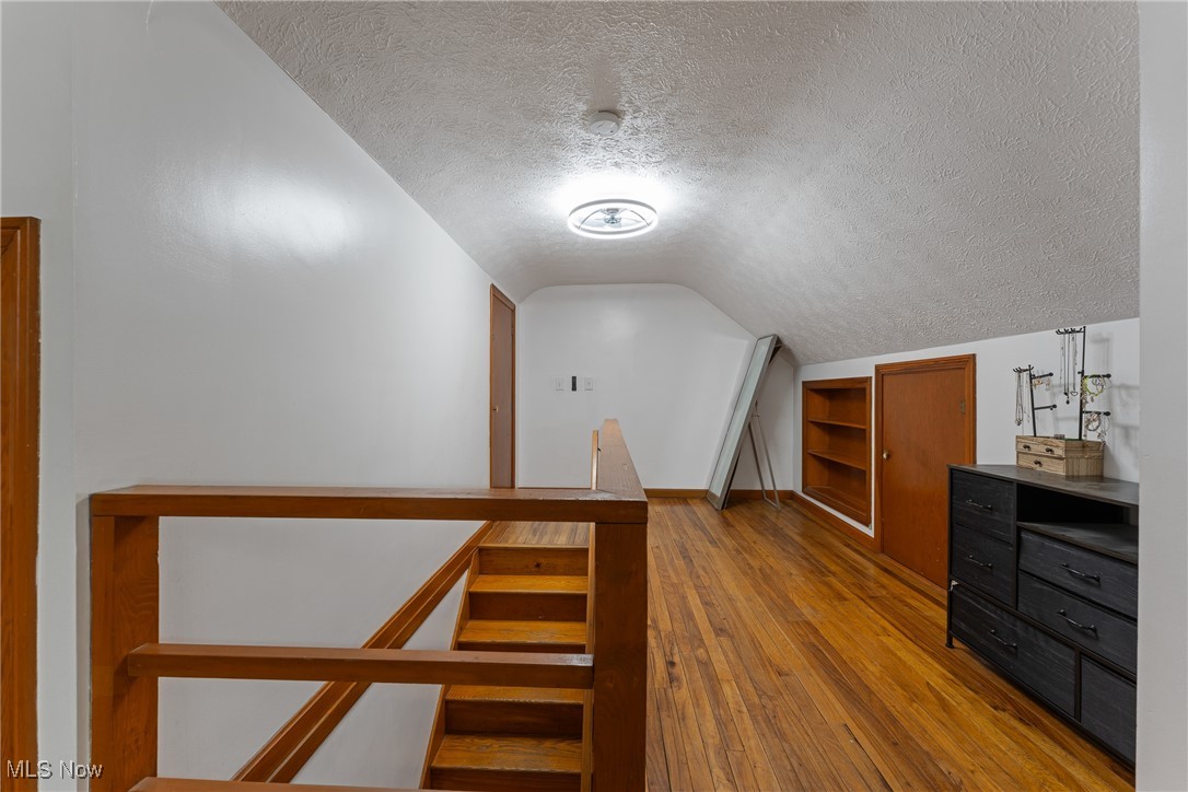 123 North Seneca Street Rittman, OH 44270 - Photo 17 of 32 Additional living space featuring wood-type flooring, lofted ceiling, a textured ceiling, and baseboards