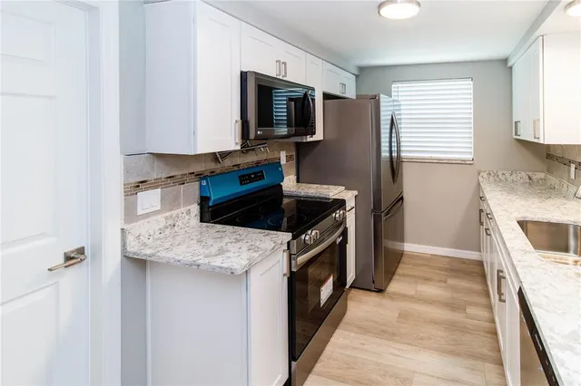 a kitchen with stainless steel appliances granite countertop a sink stove and microwave