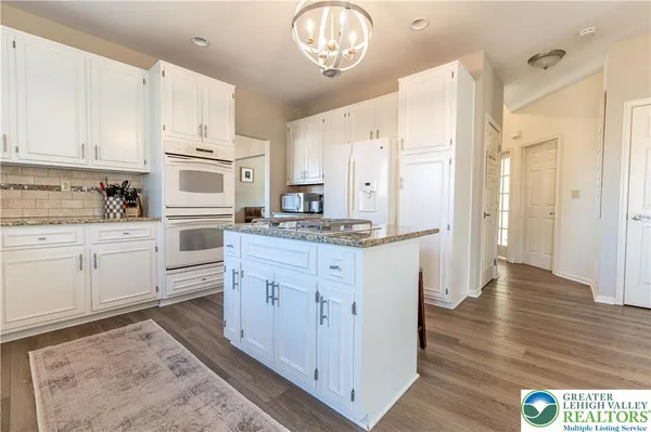 a kitchen with white cabinets and chandelier