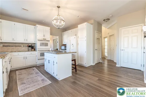 a kitchen with stainless steel appliances granite countertop a refrigerator a stove and white cabinets with wooden floor