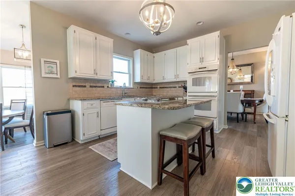 a kitchen with stainless steel appliances granite countertop wooden floors and white cabinets