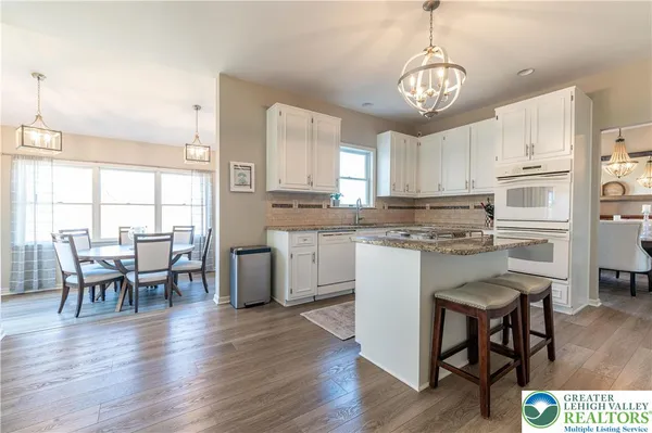 a kitchen with stainless steel appliances granite countertop a stove top oven a refrigerator a dining table and chairs with wooden floor