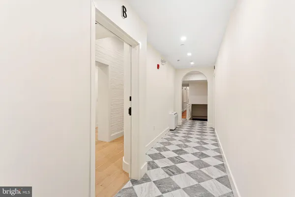a view of a hallway with wooden floor and a bathroom