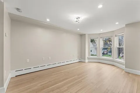 a view of an empty room with a window and wooden floor