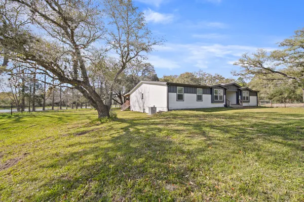 a kitchen with stainless steel appliances kitchen island granite countertop a stove a sink a refrigerator and white cabinets with wooden floor
