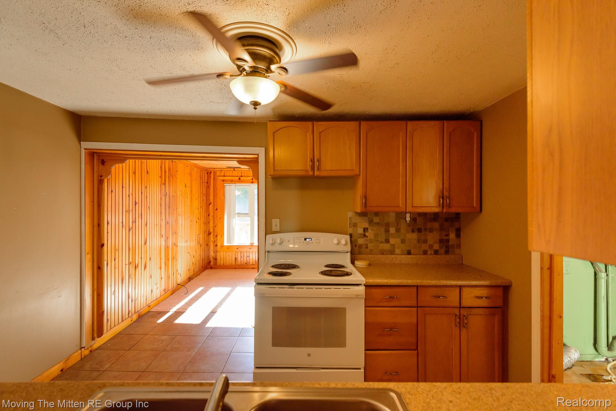 26247 Weigel Road New Boston, MI 48164 - Photo 8 of 30 Kitchen featuring warm wood-finish cabinetry, tile backsplash, and a built-in electric range