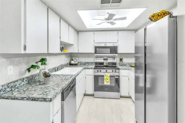 a kitchen with stainless steel appliances granite countertop a sink a refrigerator a stove a washer and dryer