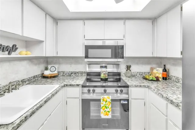 a kitchen with stainless steel appliances granite countertop a sink a stove and a white cabinets