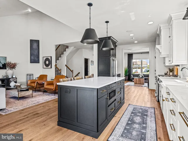 a large kitchen with kitchen island a stove a sink a refrigerator and a dining table view