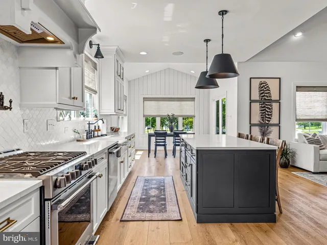 a kitchen with stainless steel appliances granite countertop a stove a sink dishwasher a refrigerator and white cabinets with wooden floor