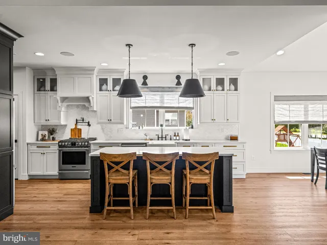 a kitchen with stainless steel appliances granite countertop a stove top oven a sink dishwasher and white cabinets with wooden floor