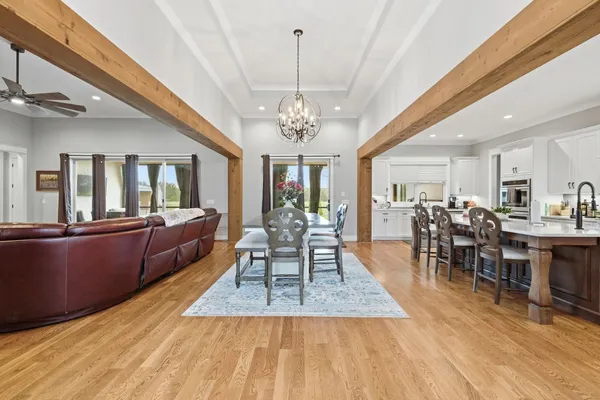 a dining room with wooden floor a chandelier a wooden table and chairs