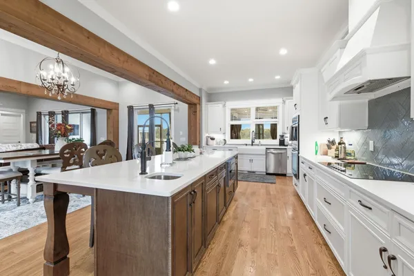 a large kitchen with kitchen island a sink a stove a dining table and chairs