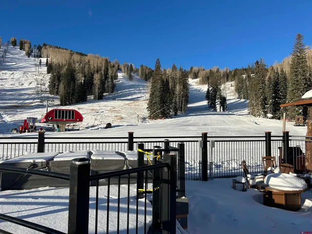 a roof deck with table and chairs and potted plants