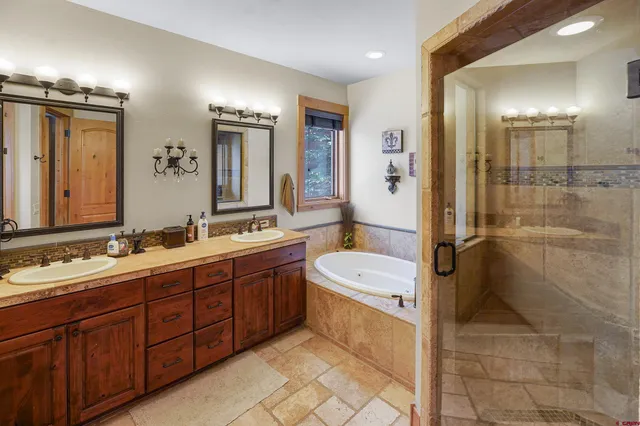 a spacious bathroom with a double vanity sink toilet mirror and bathtub