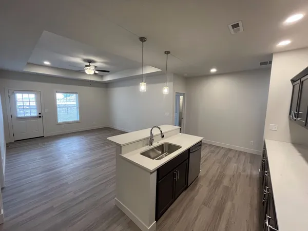a kitchen that has a sink a microwave oven a stove and white cabinets with wooden floor