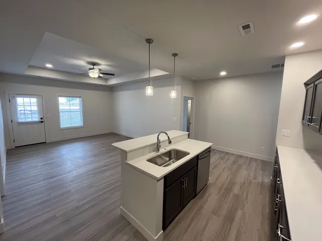 a kitchen that has a sink a microwave oven a stove and white cabinets with wooden floor
