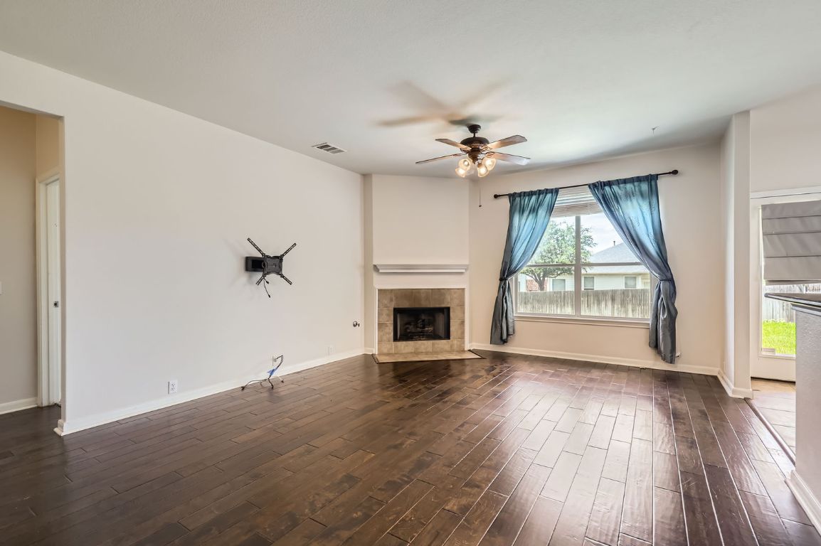 3423 Shiraz Loop Round Rock, TX 78665 - Photo 6 of 28 an empty room with windows fireplace and wooden floor
