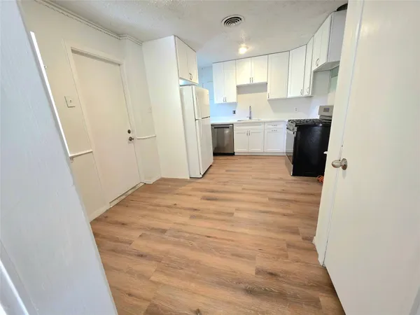 a view of a kitchen with refrigerator and white cabinets