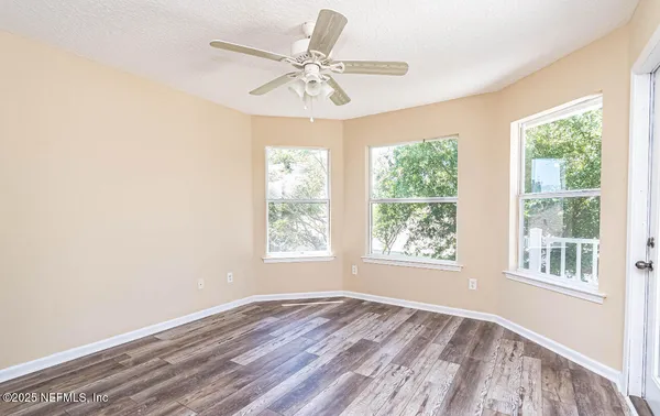 a view of an empty room with a window and wooden floor