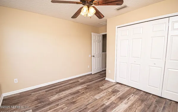 a view of empty room with wooden floor and fan