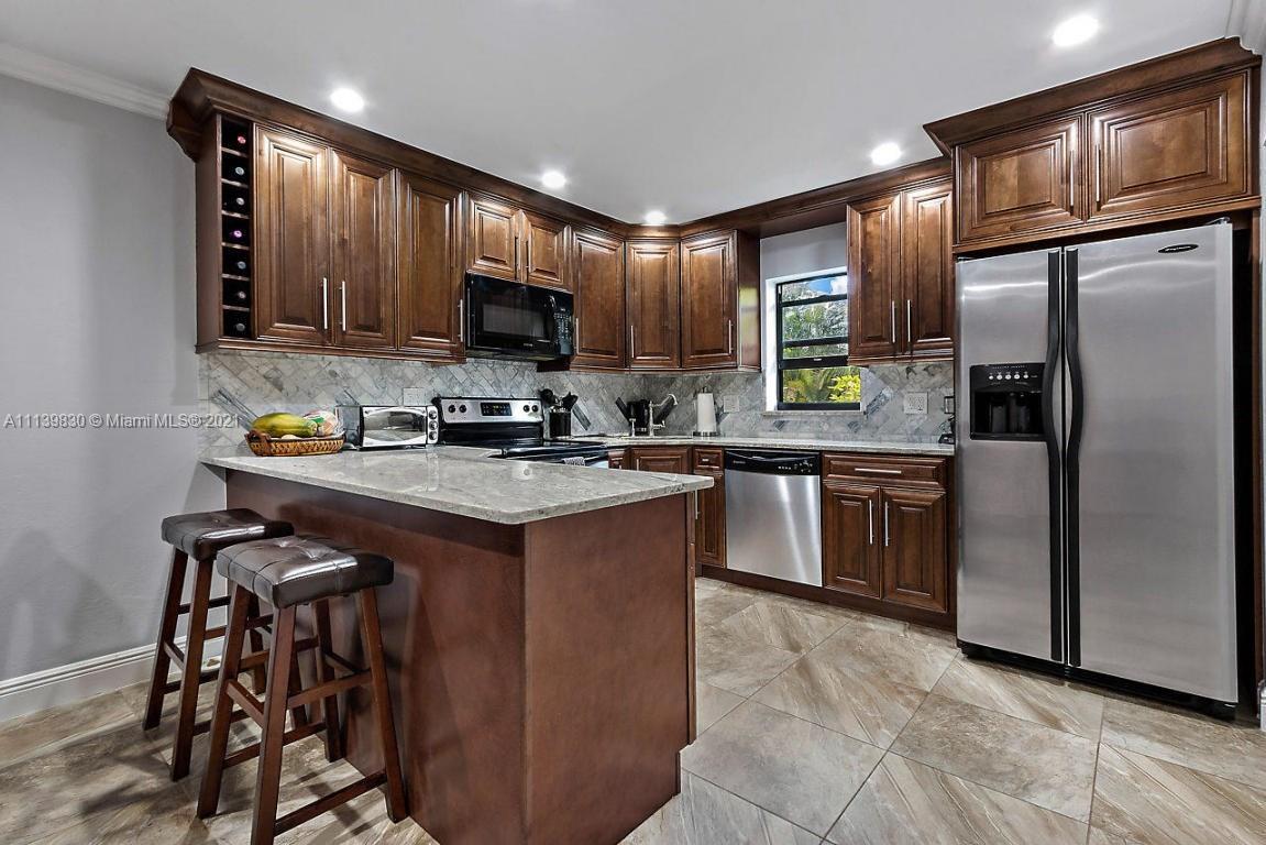 9290 Southwest 61st Way, Unit C Boca Raton, FL 33428 - Photo 4 of 4 a kitchen with stainless steel appliances granite countertop a stove a sink a microwave a refrigerator and cabinets