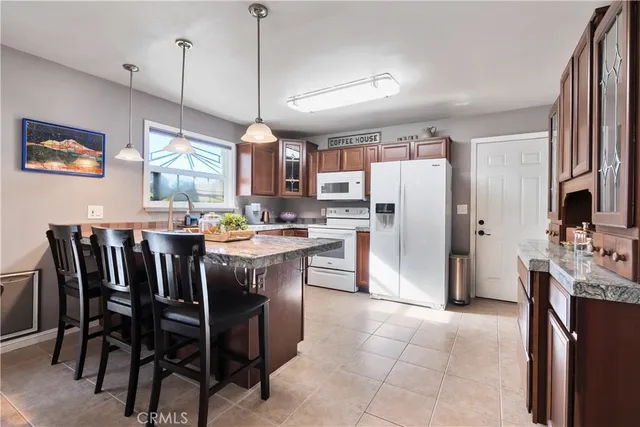 a kitchen with granite countertop a table chairs stainless steel appliances and cabinets
