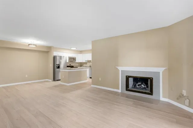 an empty room with wooden floor fireplace and windows