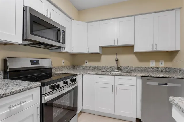 a kitchen with stainless steel appliances granite countertop a stove a refrigerator and a microwave