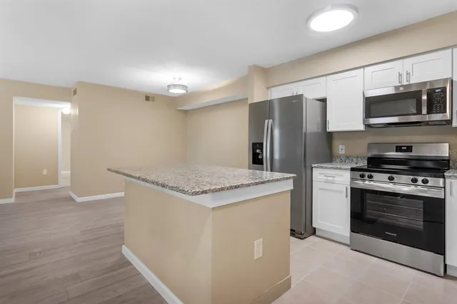 a kitchen with stainless steel appliances granite countertop a refrigerator and a stove top oven