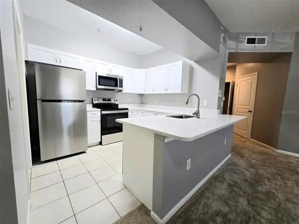 a kitchen with stainless steel appliances granite countertop a refrigerator a stove a sink a microwave and a refrigerator