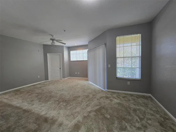 an empty room with windows and chandelier fan
