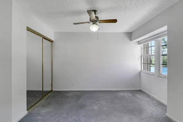 an empty room with windows and ceiling fan