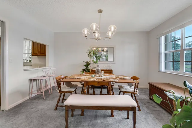 a view of a dining room with furniture a chandelier and a window