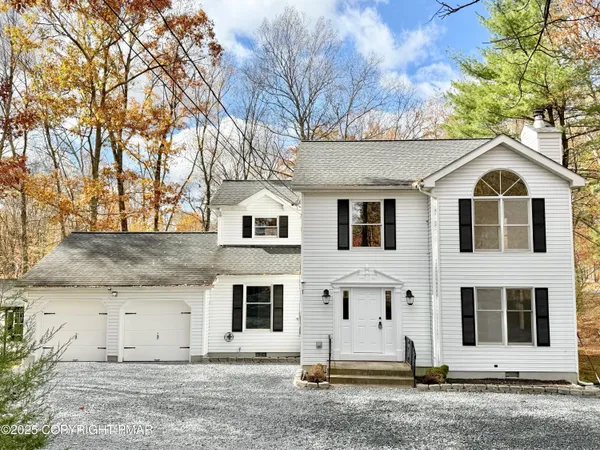 a view of a white house with a large tree