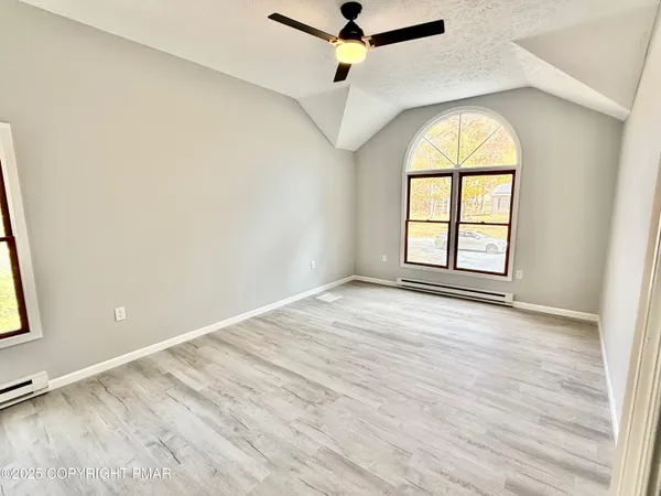 an empty room with wooden floor chandelier fan and windows