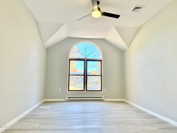 an empty room with wooden floor chandelier and windows