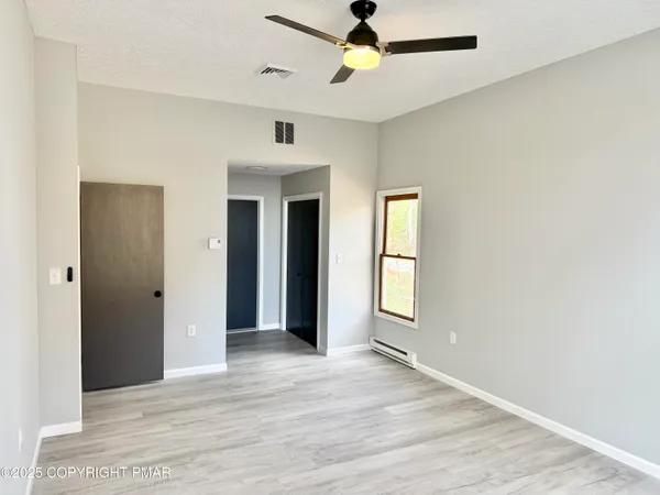 a view of an empty room with window and wooden floor
