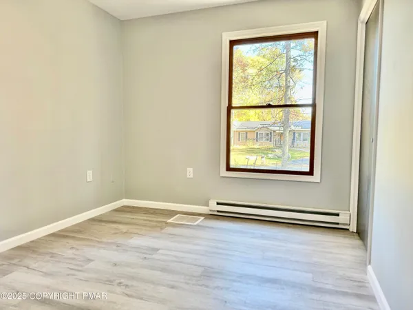 an empty room with wooden floor and windows